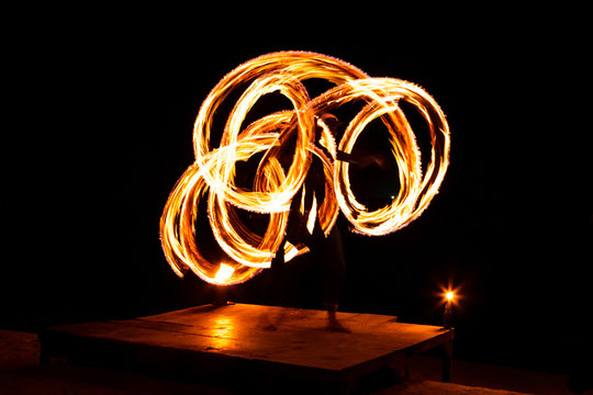 Street artist fire juggling performance. Light painting and long exposure picture to form trails. Phi Phi Island, Thailand.