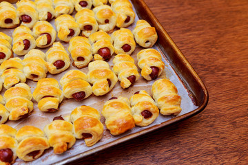 Homemade sausages in the dough. Hot wrapped dough sausages on baking sheet