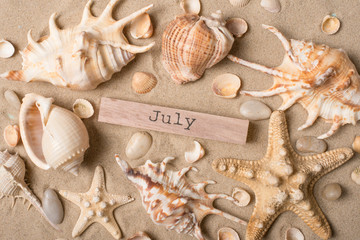 Fototapeta na wymiar The inscription June on sand with starfish and seashells