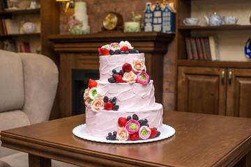 Three tiered pink wedding cake decorated with berries and flowers. Concept patisserie floristic from sugar mastic