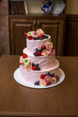 Three tiered pink wedding cake decorated with berries and flowers. Concept patisserie floristic from sugar mastic