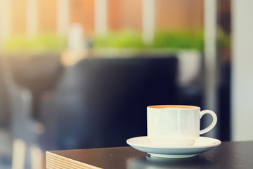 Latte Coffee in a cup on wooden table and Coffee shop blur background