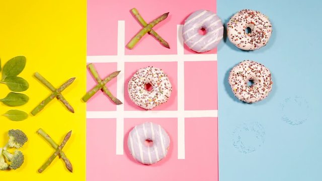 Playing in tik tak toe game with donuts and asparagus. Health nutrition concept image