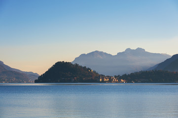 Evening sunset at Como lake with small boat at foreground and mountains at background, Italy