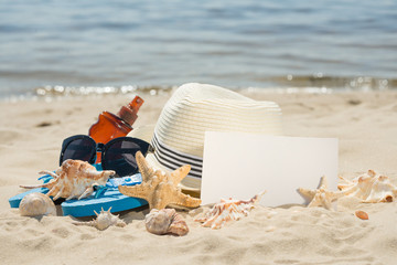 Hat on the beach, sunglasses, seashells and a star. On white sand, with an empty place for inscription