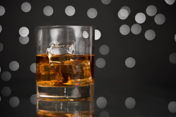 Whiskey in a glass with ice on a dark background with a bokeh