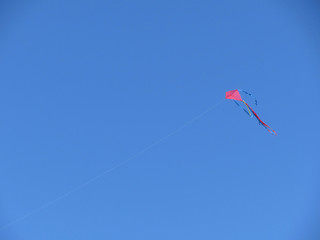 Single red flying kite on a clear blue sky