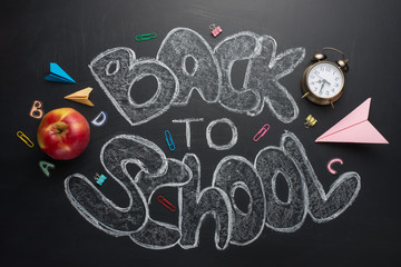 Back to school, the inscription is white chalk on a black school board, with an apple clock and a cancical