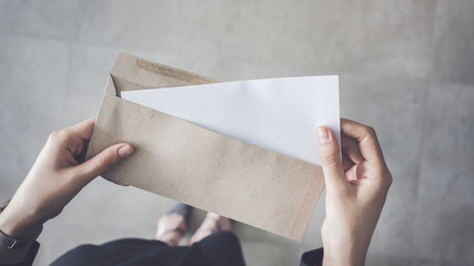 Stand up woman holding white folded a4 paper and brown envelope - obrazy, fototapety, plakaty