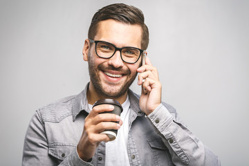 Portrait of happy young man talking on phone and drinking tea. Isolated white background.