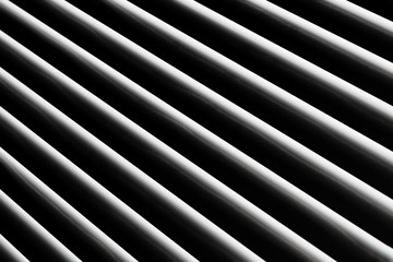 An abstract snapshot of a close-up illuminated grille that is angled with a dark background for patterns and backgrounds.