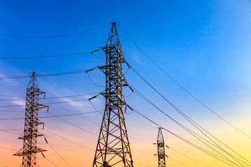 High voltage electricity pylons and transmission power lines on the blue sky background.