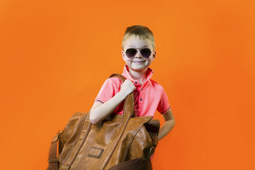 cute boy with a suitcase on a bright orange background
