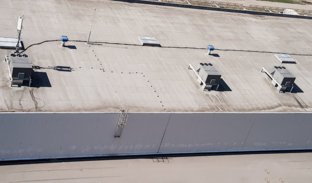 Roof of a commercial building with a external units of the commercial air conditioning and ventilation systems.