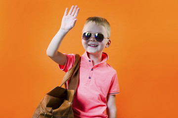 cute boy with a suitcase on a bright orange background