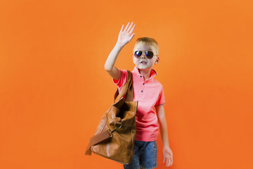 cute boy with a suitcase on a bright orange background