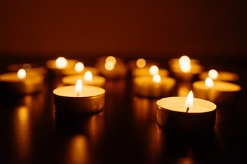 Burning candles. Shallow depth of field. Many christmas candles burning at night. Abstract candles background. Many candle flames glowing on dark background. Close-up. Free space.