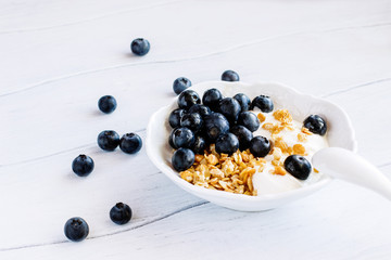 Healthy  breakfast granola with blueberries and yogurt in a bowl on a white table