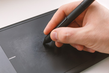 Men's hand draws on a graphics tablet using a stylus