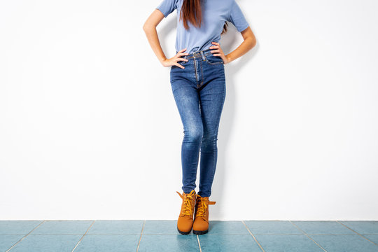Young girl blue jeans brown shoes wall white.