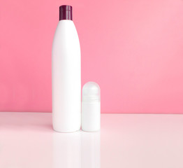 Body care products on white table over pink background, copy space