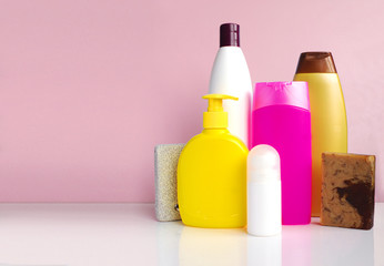Body care products on white table over pink background, copy space