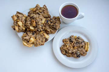 Homemade oatmeal cookies on plate with cap of tea on the white background.