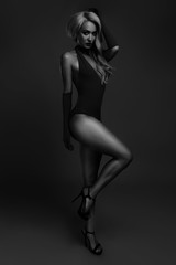 black and white photo of a girl in a swimsuit on a dark background.