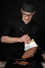 Chocolatier in black uniform in the process of making chocolates