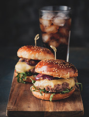 Street food, fast food. Homemade juicy burgers with beef, cheese and caramelized onions on the wooden table. - obrazy, fototapety, plakaty