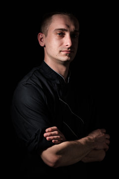 portrait of a young chef in uniform on a black background.
