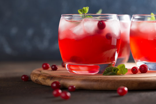 Vivid summer refreshing drink with cranberry, ice cubes and mint on the cutting board.