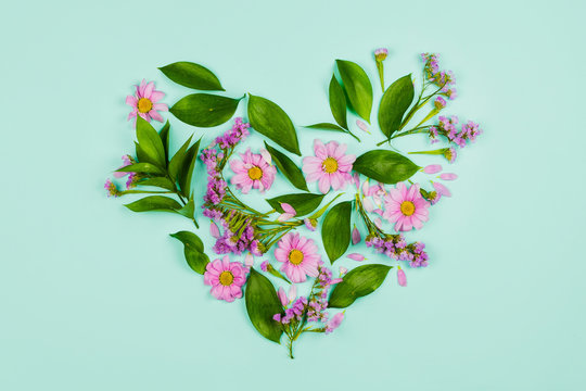 Fototapeta Heart made of leaves, violet and pink flowers. Blue pastel background.