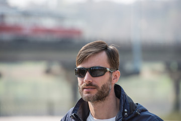 portrait of a bearded man in sunglasses looks around.