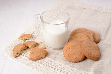 Homemade ginger cookies with a glass of milk on a wooden light b