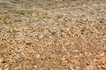 Yellow underwater peeble texture background.Small stones under the water surface.Various colorful wet pebbles texture as natural background.