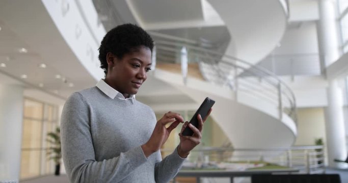 African American using smartphone in modern office
