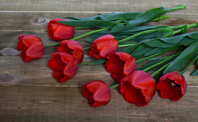 Bouquet of red fresh tulips on a wooden table. Spring and celebration concept background. 