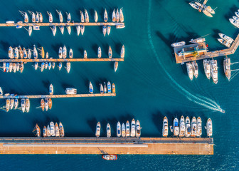 Luftaufnahme von erstaunlichen Booten bei Sonnenuntergang. Minimalistische Landschaft mit Booten und Meer in der Marinabucht. Draufsicht von der Drohne auf den Hafen mit Yacht, Motorboot und Segelboot. Schöner Hafen