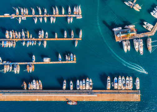 Fototapeta Aerial view of amazing boats at sunset. Minimalistic landscape with boats and sea in marina bay. Top view from drone of harbor with yacht, motorboat and sailboat. Beautiful port