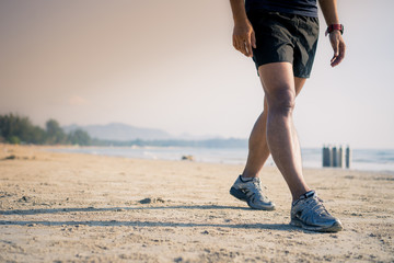 Athlete man runner legs running closeup on shoe,Men jogging on the beach 
