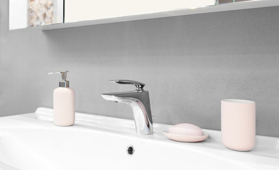 Luxury modern style faucet mixer on a white sink in a beautiful gray and white bathroom with pink...