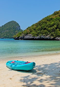 A turquoise kayak on a beach on the island of Ko Mae Ko (Angthong Marine National Park) in Thailand. This image can be used to represent adventure holiday activities. 