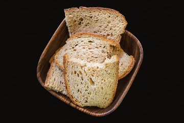 Sour yeast bread slices in the basket. Tradtional homemade bread on black background