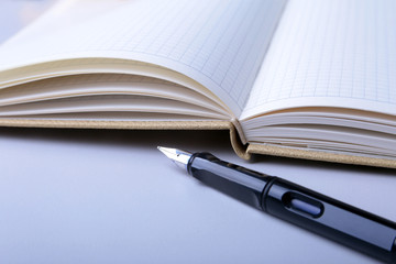 Business accessories on desktop: notebook, diary, fountain pen, glasses. Macro with blur and soft focus.