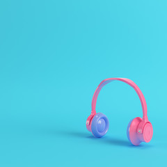 Pink headphones on bright blue background in pastel colors