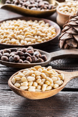 Pine nuts in the spoons on the wooden table. Macro. Organic food.