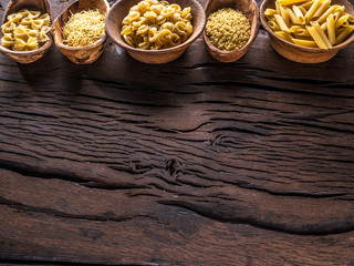 Different pasta types in wooden bowls on the table. Top view.
