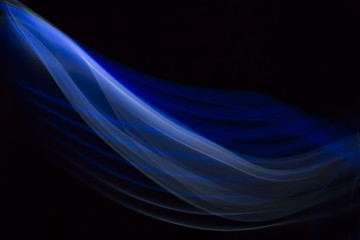Close up colorful blue and white backlit tracks of smoke and fog creating system of abstract curves and lines isolated on black background. Creative art macro photography in backlight.