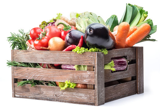 Fresh multi-colored vegetables in wooden crate.